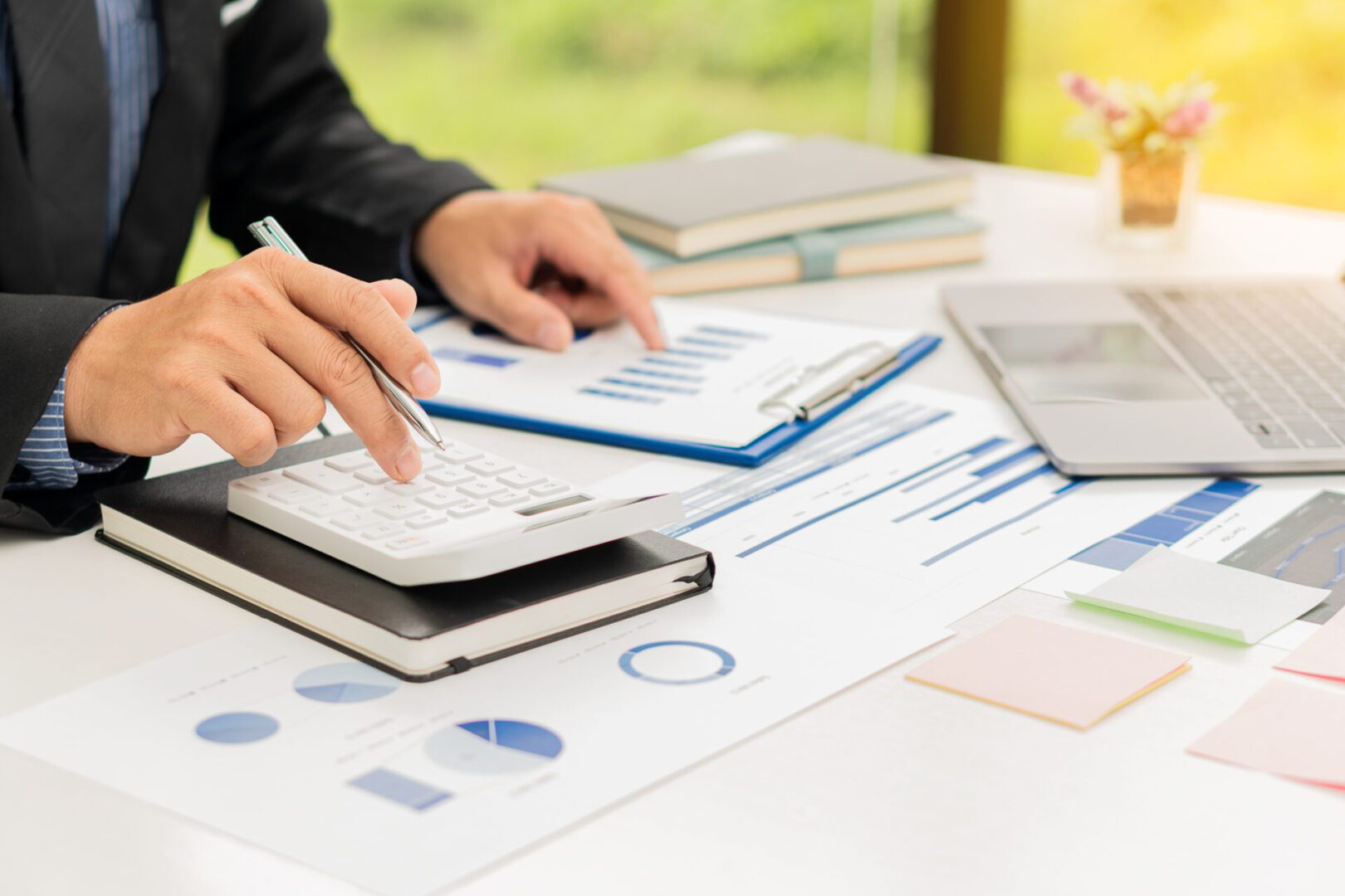 Businessman using calculator with financial documents.
